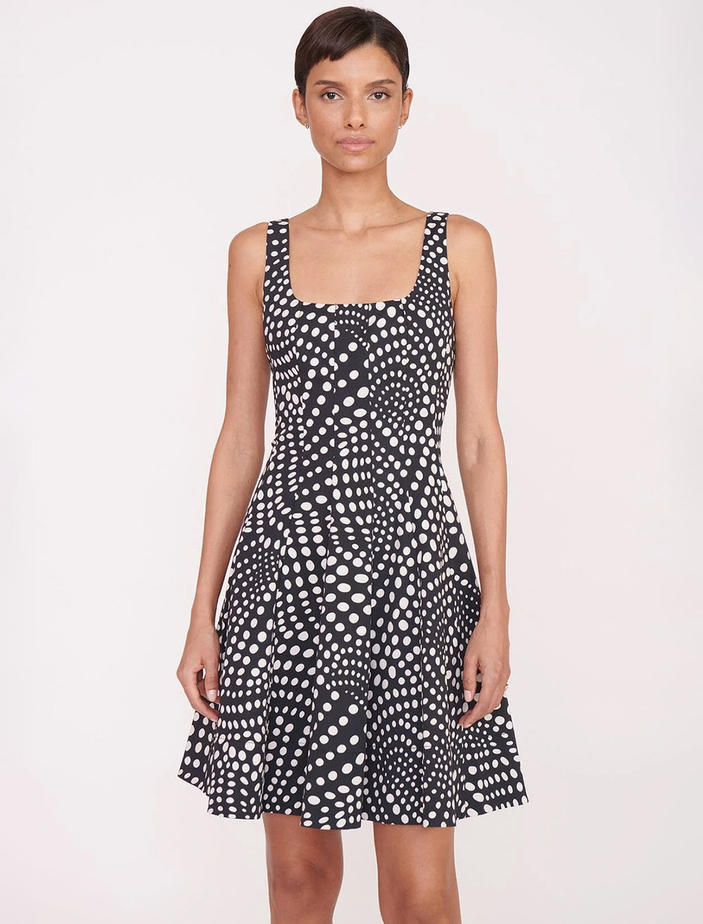 Model wearing STAUD's mini wells dress in black wavy dot.