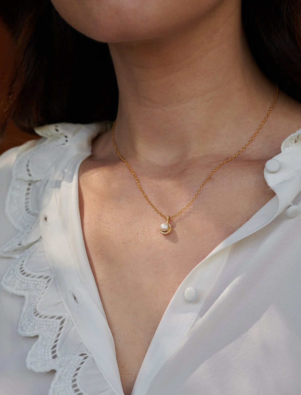 model wearing small pearl drop necklace in gold
