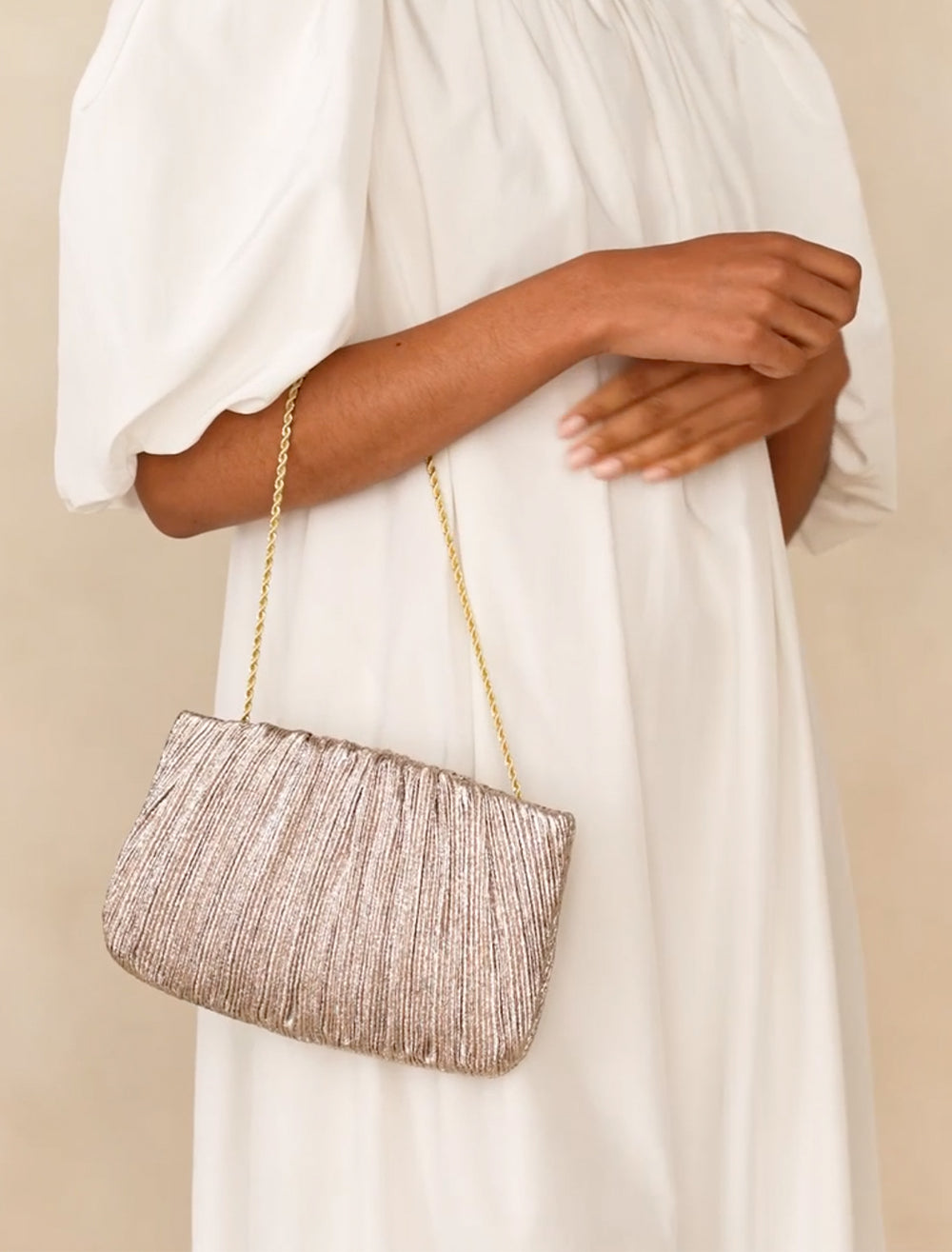 Model carrying Loeffler Randall's brit flat pleated pouch in champagne.