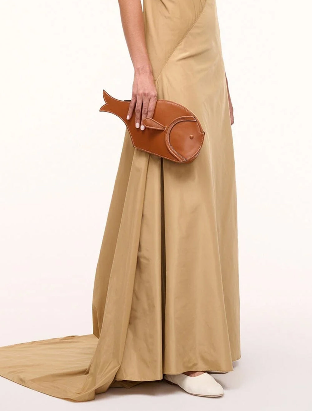 Model holding STAUD's pesce leather clutch in tan.