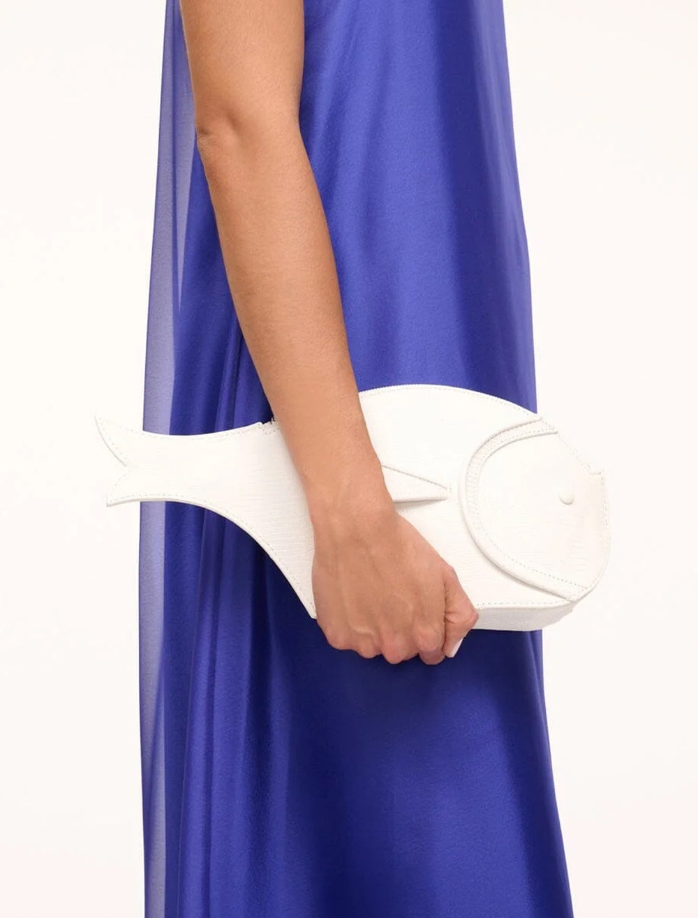 Model carrying STAUD's pesce leather clutch in paper.