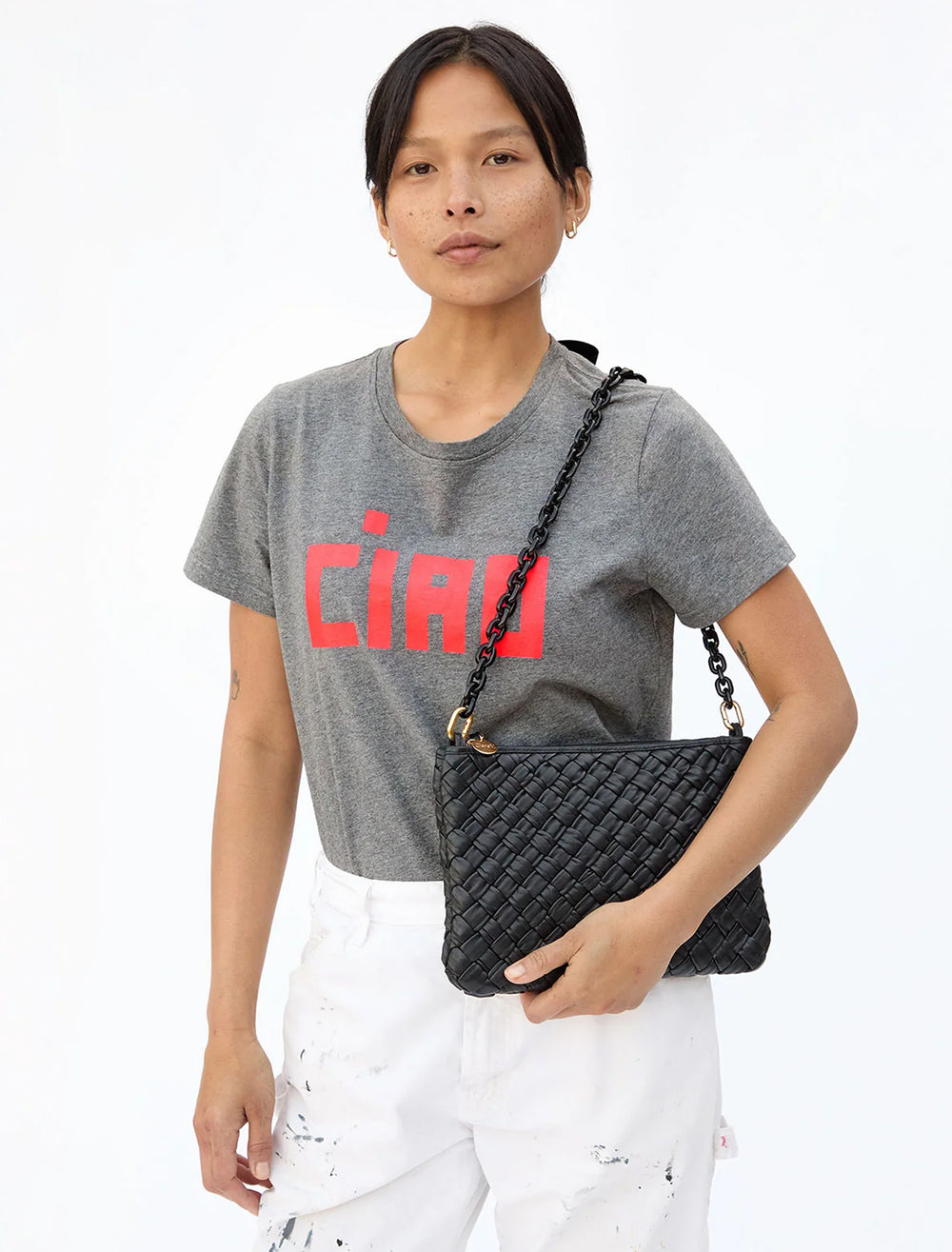 Model wearing Clare V.'s mini resin link shoulder strap in black on her shoulder.