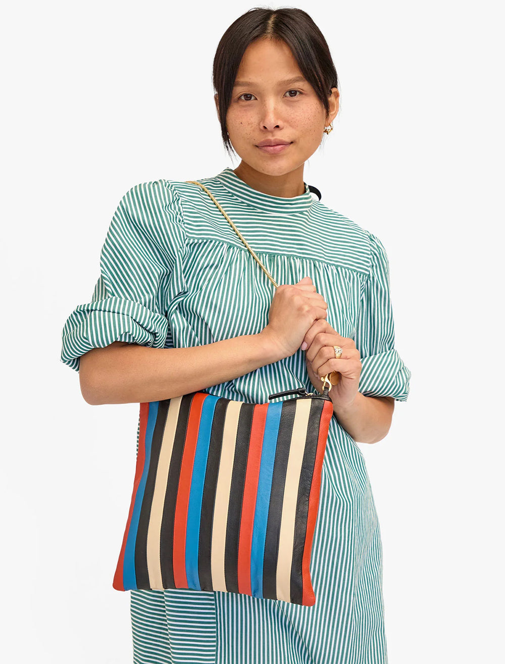 Model wearing Clare V.'s foldover clutch with tabs in multi stripe nappa as a shoulder bag.