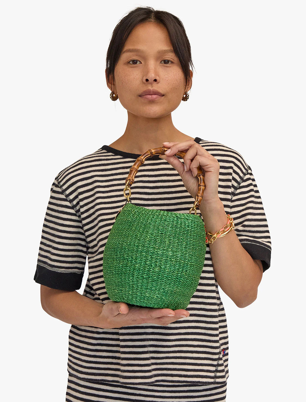 Model holding Clare V.'s pot de miel in green with bamboo handle.
