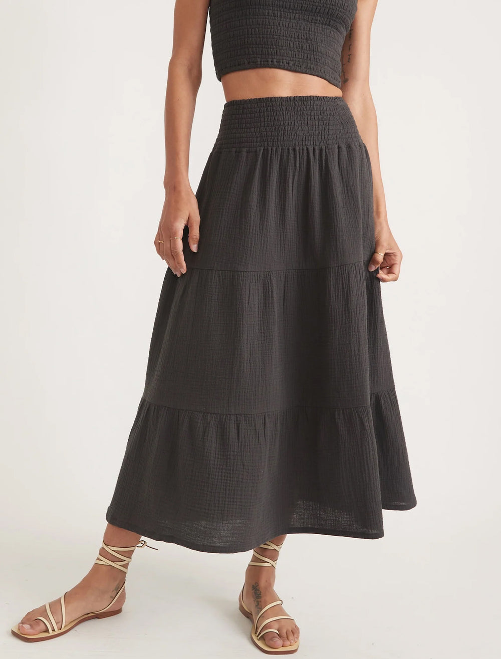 Model wearing marine layer's corinne smocked waist maxi skirt in black.