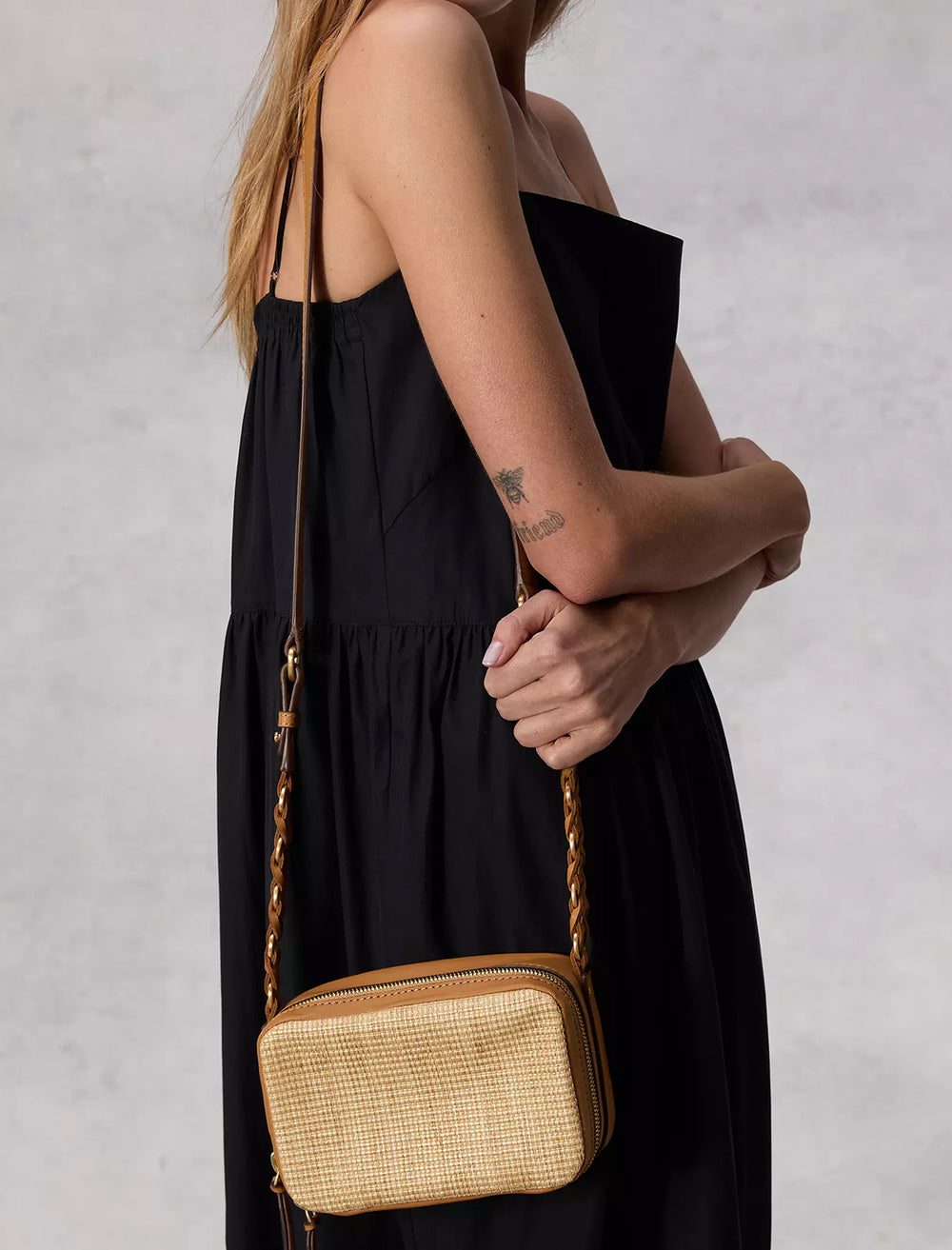 Model wearing Rag & Bone's cami straw cameral bag in natural on her shoulder.
