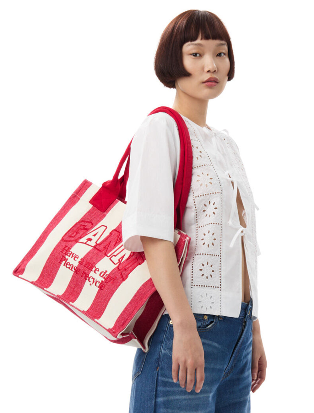 Mdel wearing GANNI's large easy shopper in barbados cherry stripe on her shoulder.