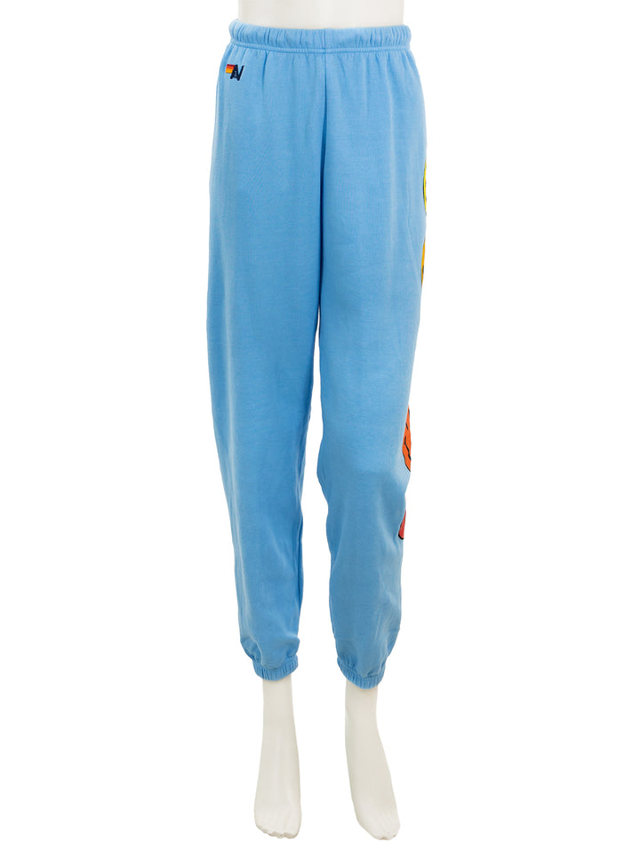 Front view of Aviator Nation's smiley sunset womens sweatpants in sky.