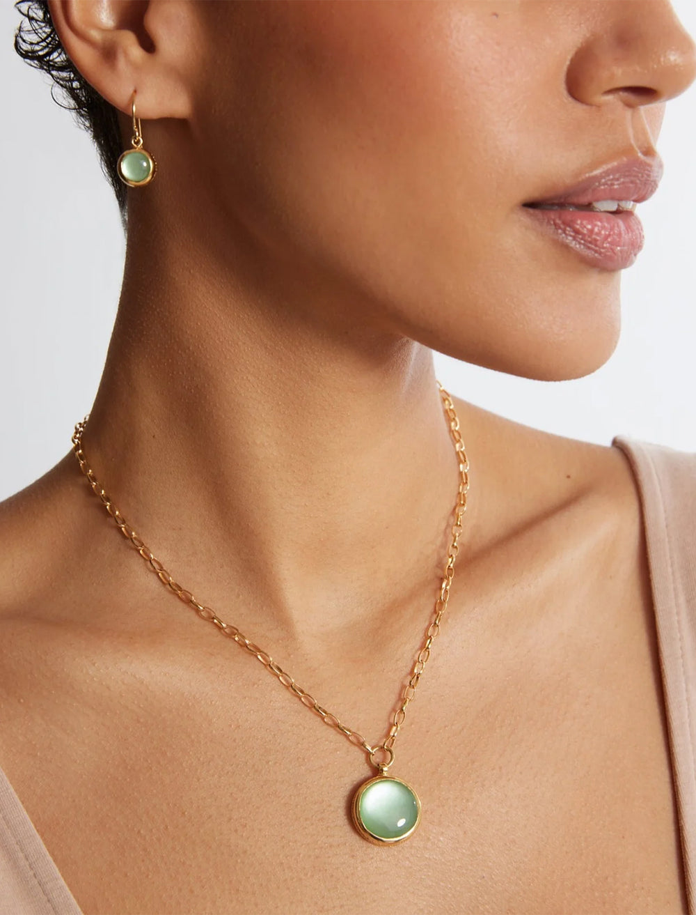 Model wearing Anna Beck's green quartz drop earrings in gold.
