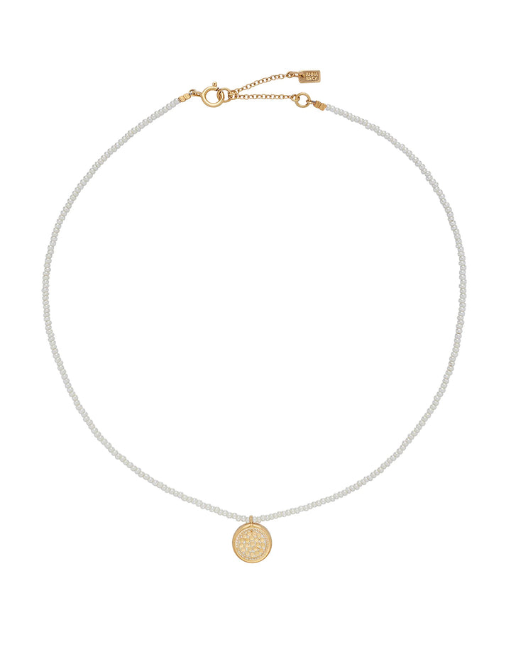 Overhead view of Anna Beck's delicate beaded pearl circle pendant necklace in gold.