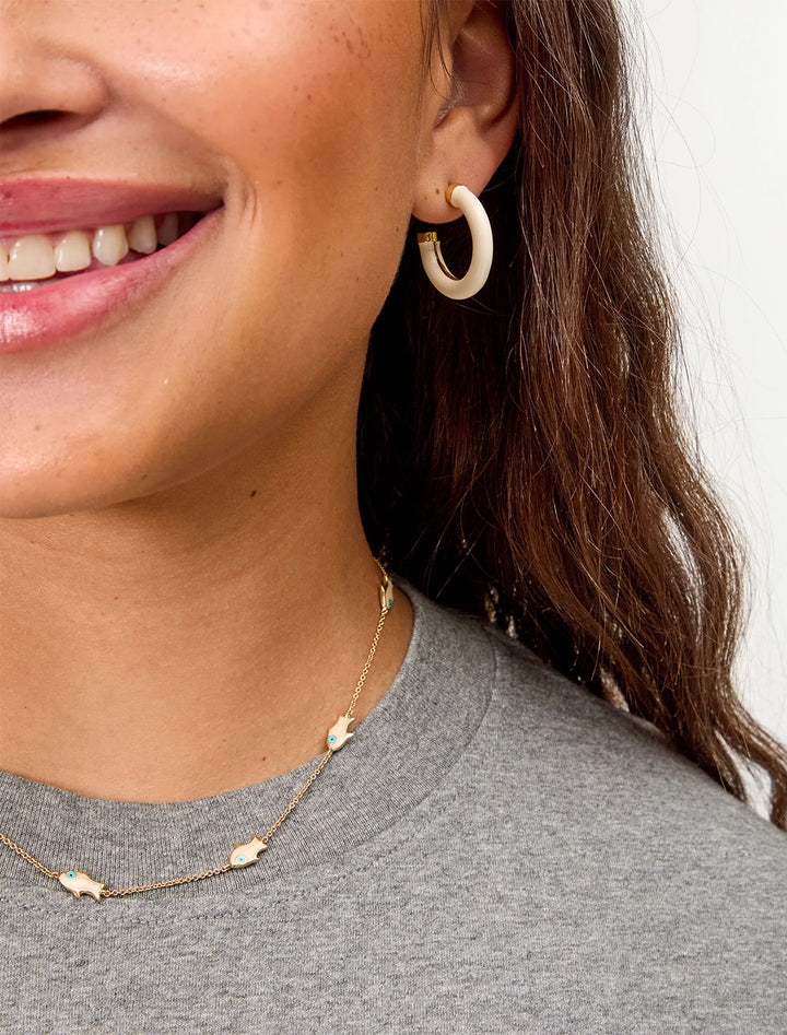 model wearing le tube hoop earrings in cream