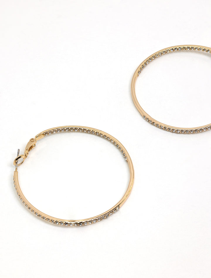 Stylized laydown of AV Max's large rhinestone hoops in gold.