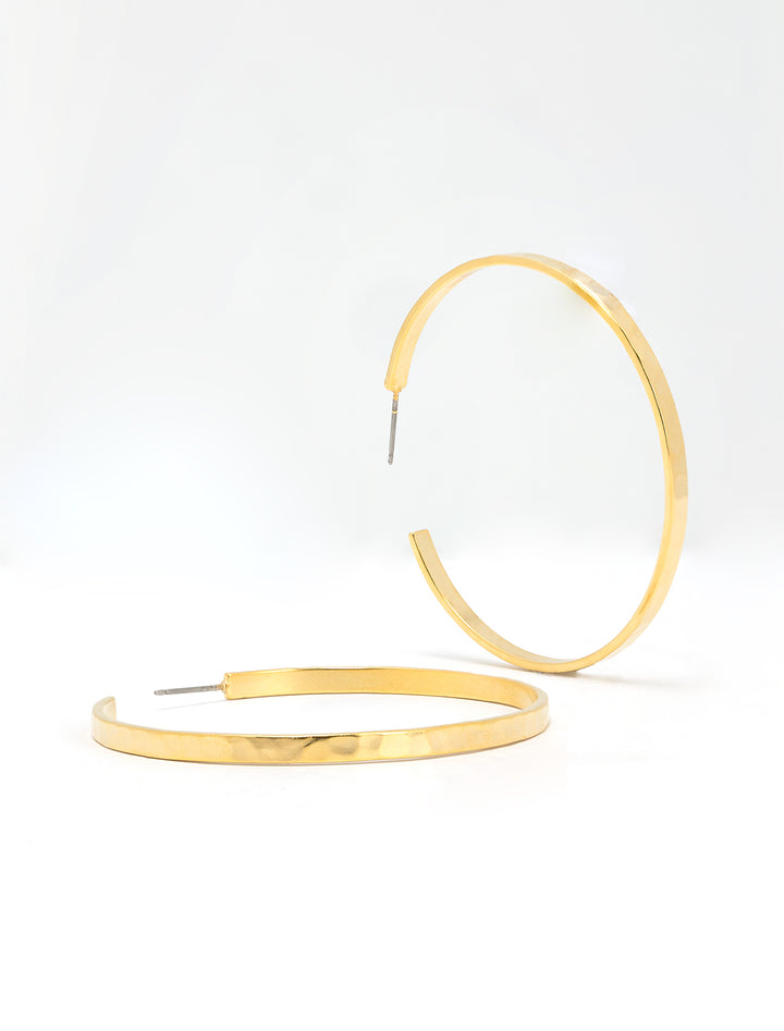 Stylized laydown of AV Max hammered matte gold hoops.