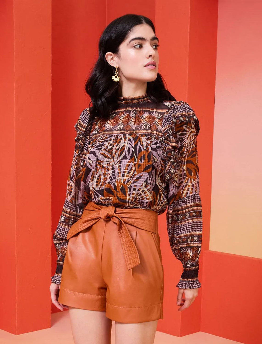 model wearing daphne blouse in orchid leaf tucked into orange leather shorts