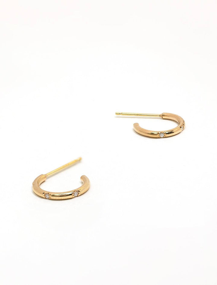 Stylized laydown of Zoe Chicco's 14k huggie hoops with bead set diamonds.