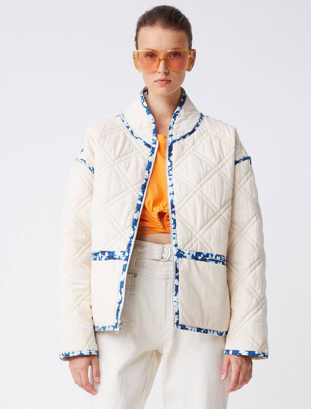Model wearing the white side of Suncoo Paris' elios reversible jacket in white and bleu.