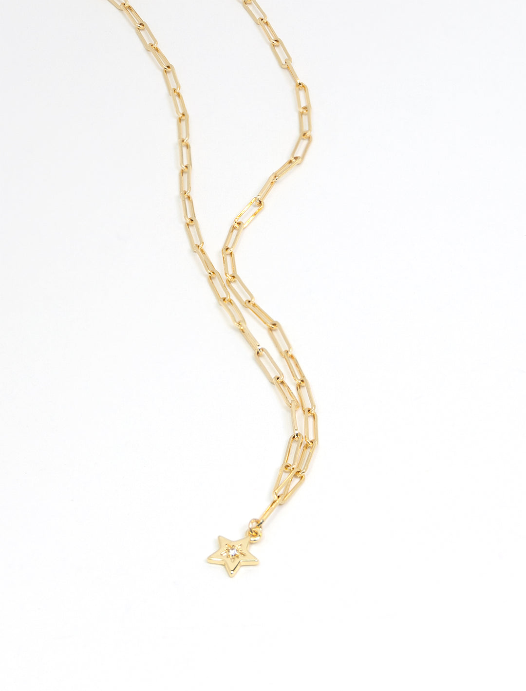 Stylized laydown of Marit Rae's star on paperclip chain necklace in gold.