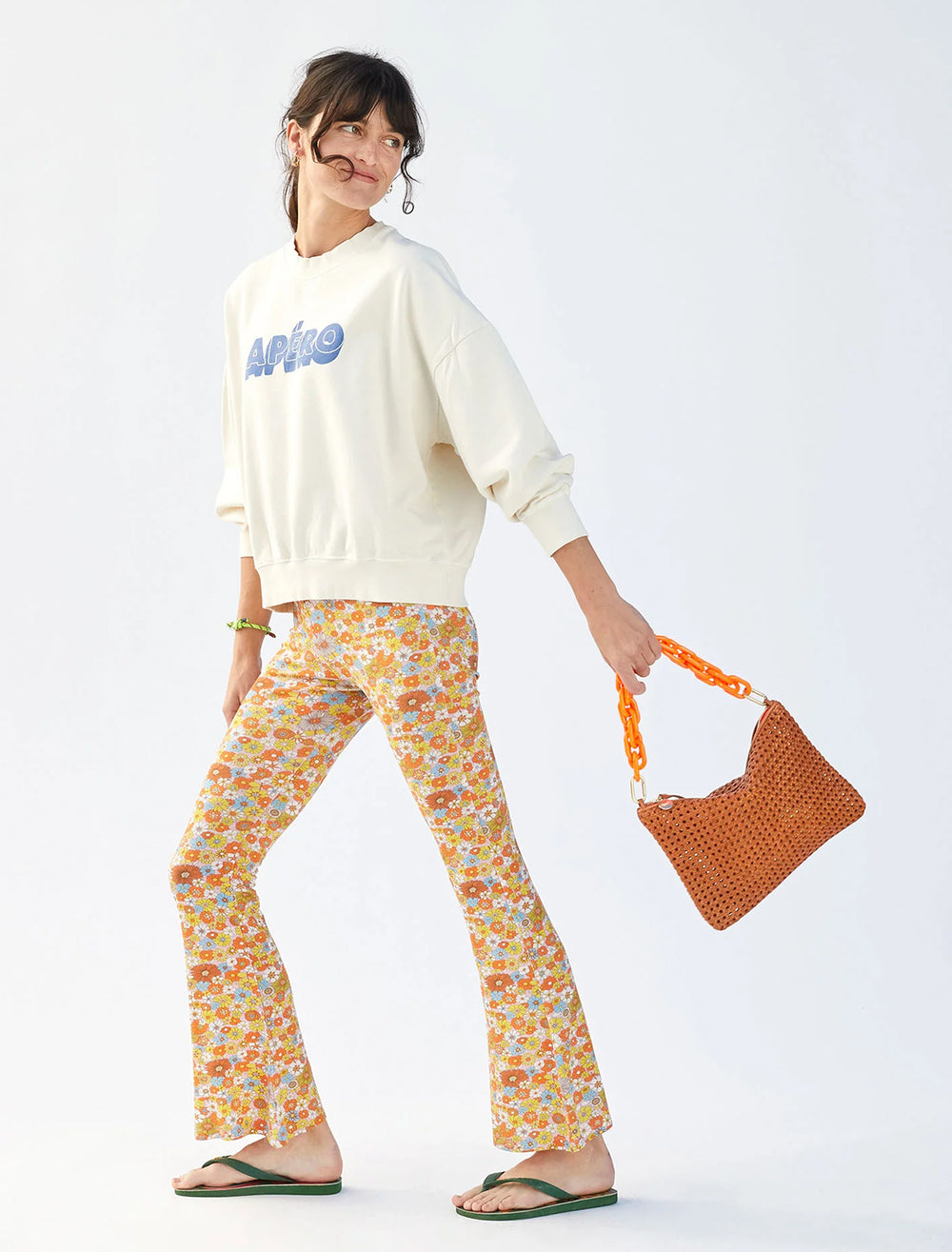 model holding flat clutch with tabs in tan rattan
