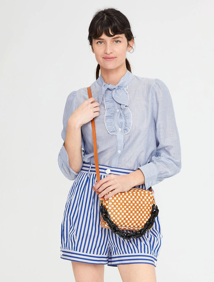 model holding midi sac in natural and cream woven checker