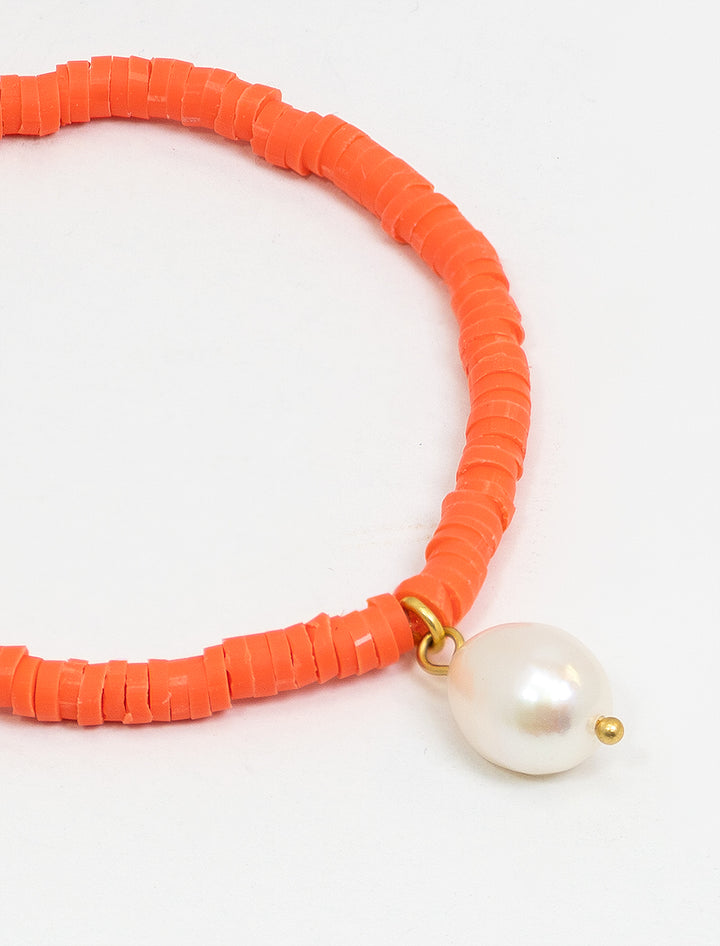 Close-up view of Clare V.'s beaded disc stretch bracelet with coral and pearl.