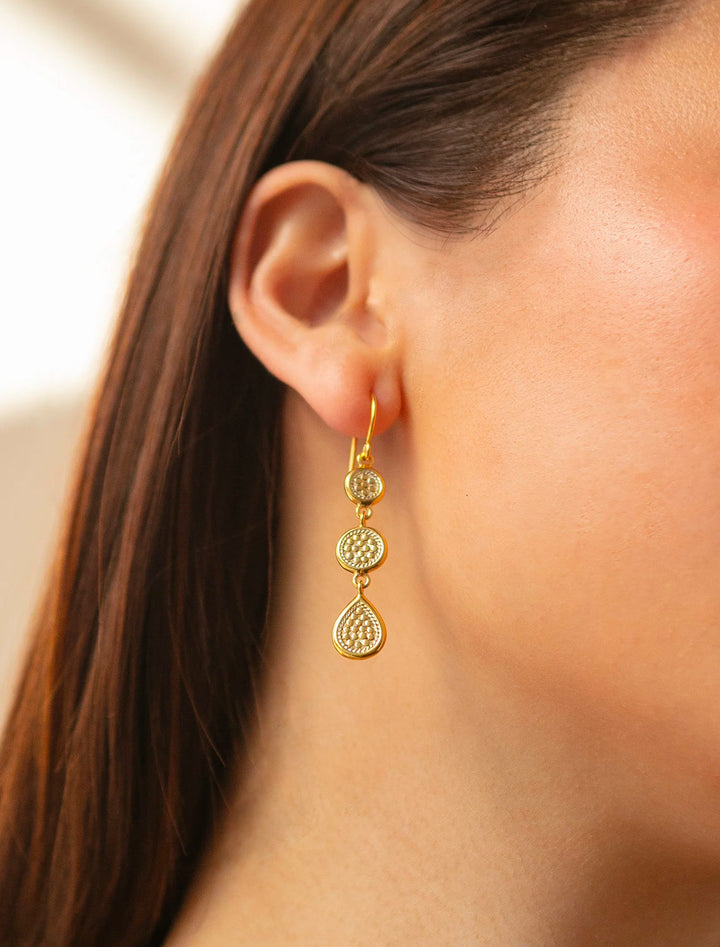 Model wearing Anna Beck's classic triple drop earrings in gold.