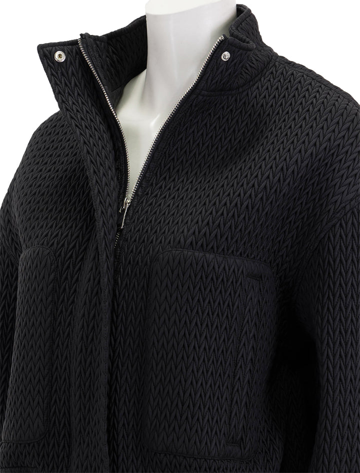 Close-up view of Essentiel Antwerp's easygoing faux leather bomber in black.