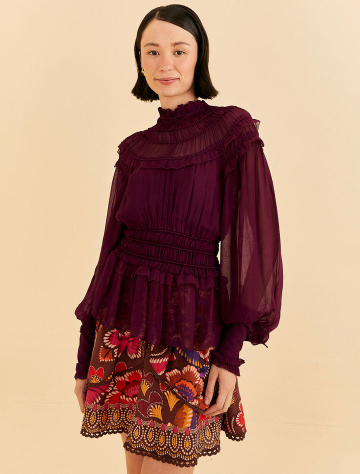 Model wearing Farm Rio's burgundy ruffled blouse.