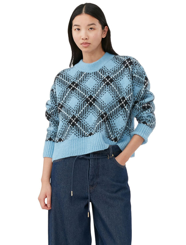 Model wearing GANNI's check wool oversized pullover in silver lake blue.