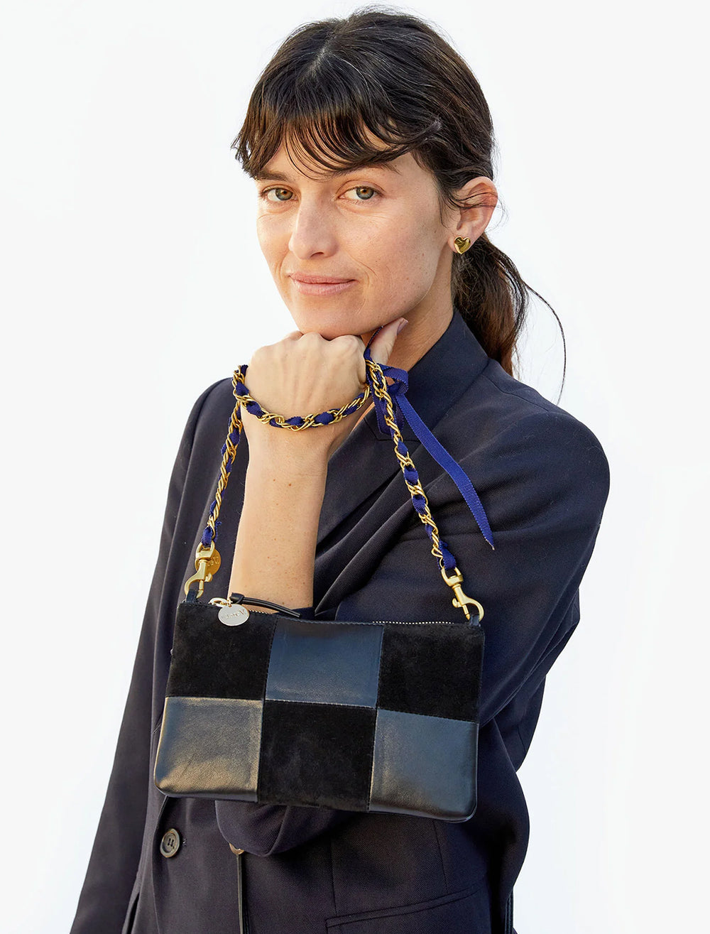 Model holding Clare V.'s wallet clutch with tabs in black suede and nappa patchwork.