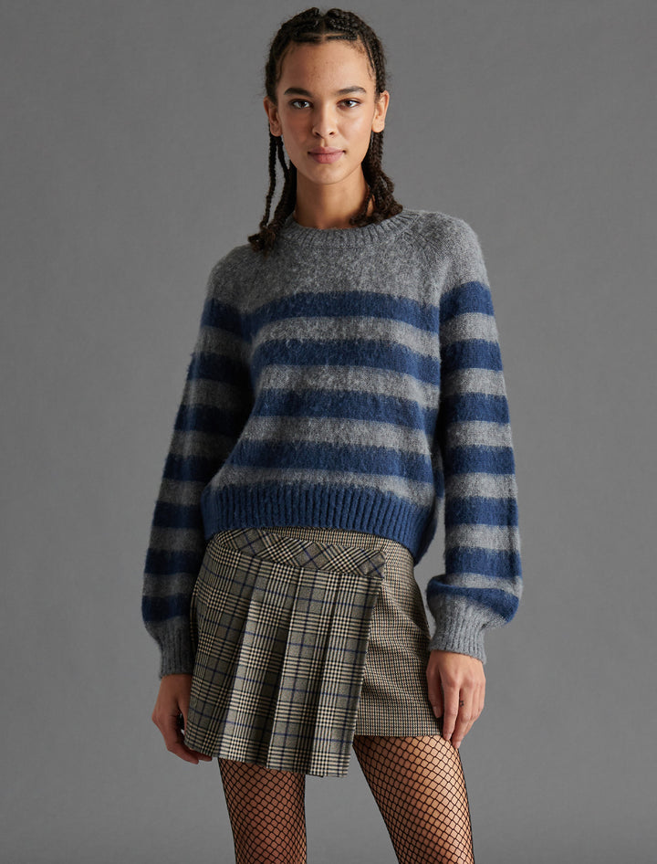 Model wearing Steve Madden's lyon sweater in grey and navy stripe.
