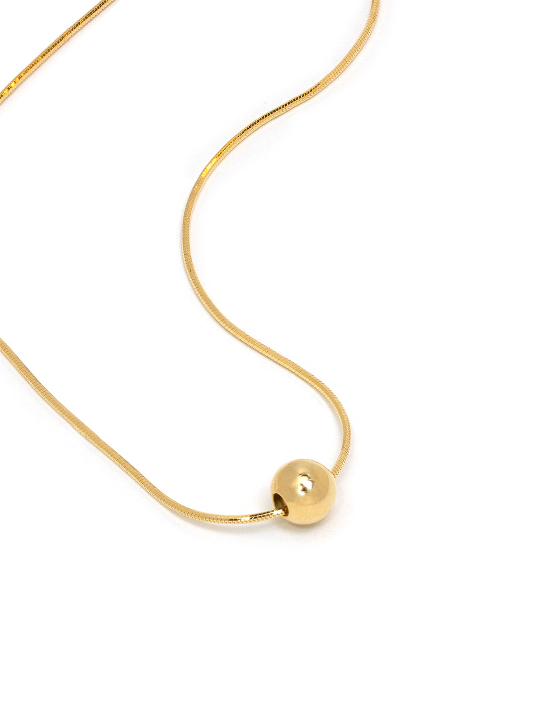 Stylized laydown of Tai's snake chain with single gold ball necklace.