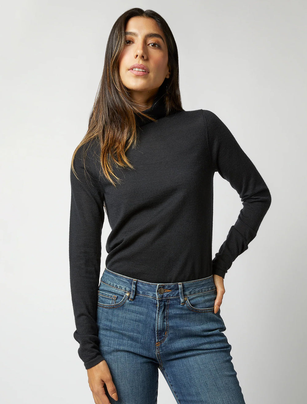 Model wearing Ann Mashburn's funnel neck cashmere sweater in black.