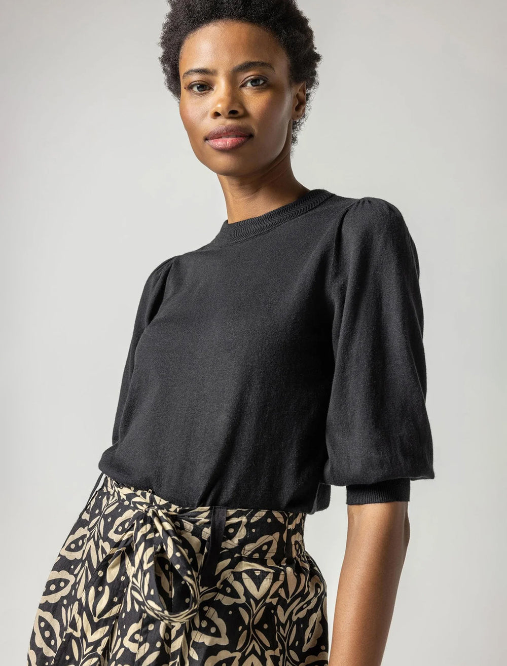 Model wearing Lilla P.'s rib trim puff sleeve sweater in black.