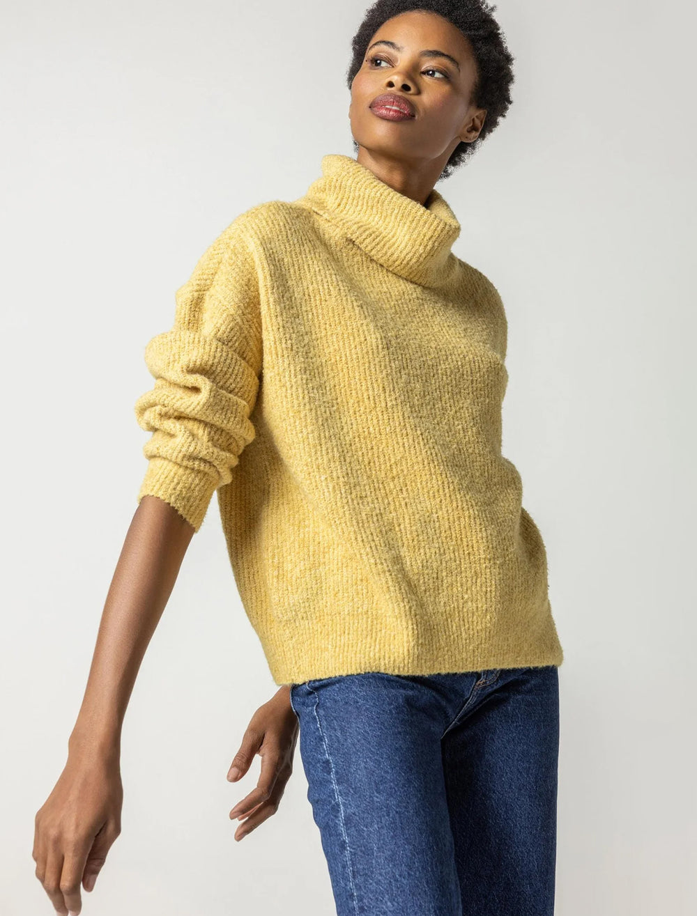 Model wearing Lilla P.'s oversized ribbed turtleneck in gold dust.