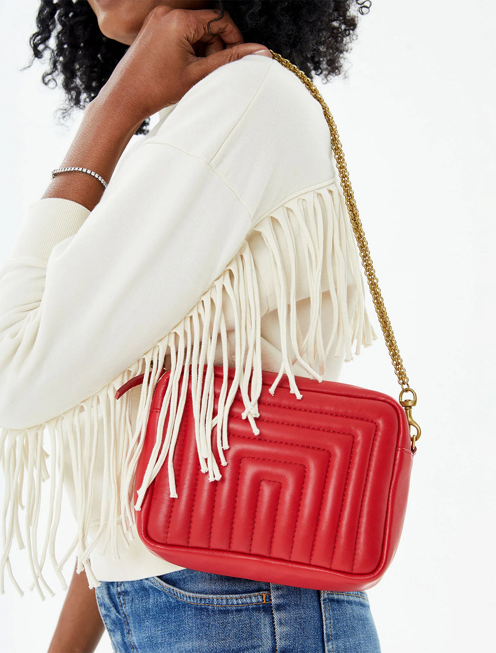 Model wearing Clare V.'s midi sac in rouge channel quilted on her shoulder.