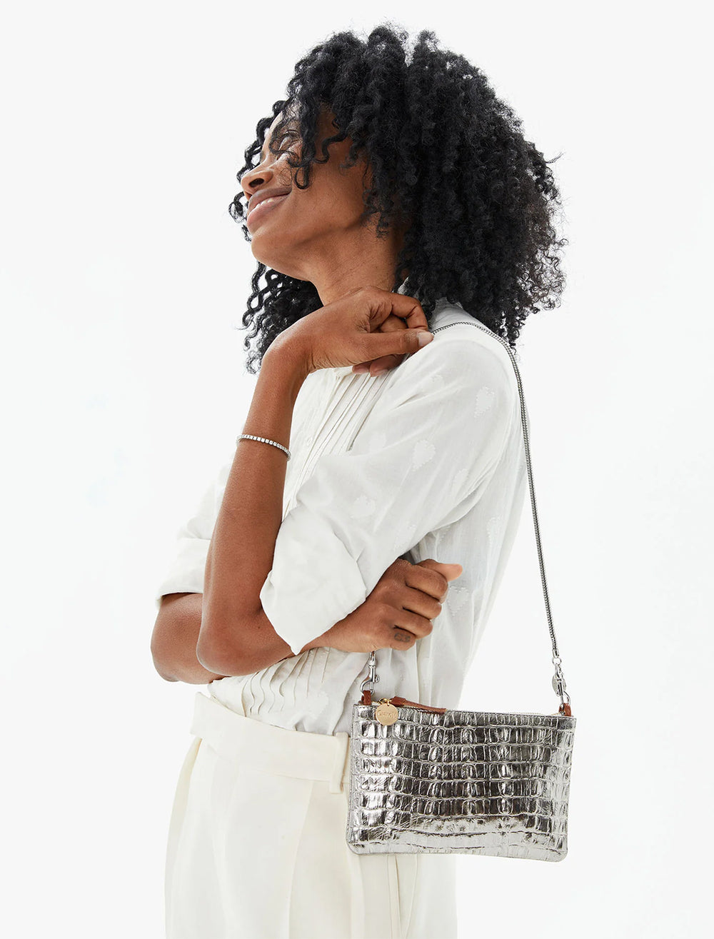 Model wearing Clare V.'s wallet clutch with tabs in silver metallic croco as a bag.