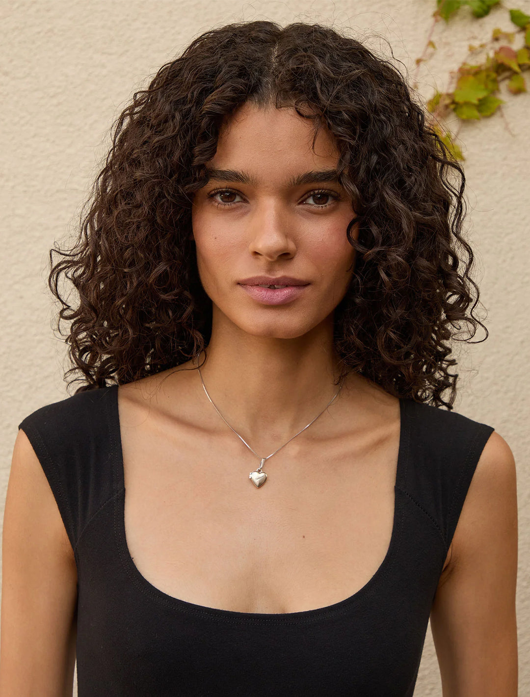 Model wearing Clare V.'s petit heart locket attached to a chain.