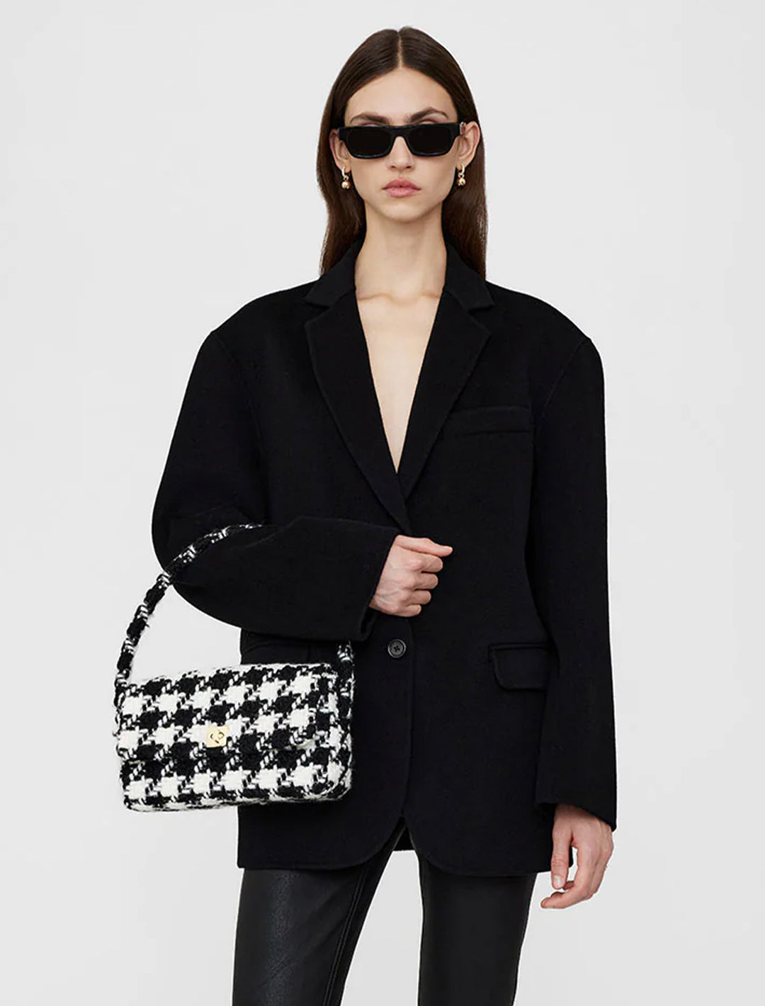 Model holding Anine Bing's nico handbag in black and white houndstooth.