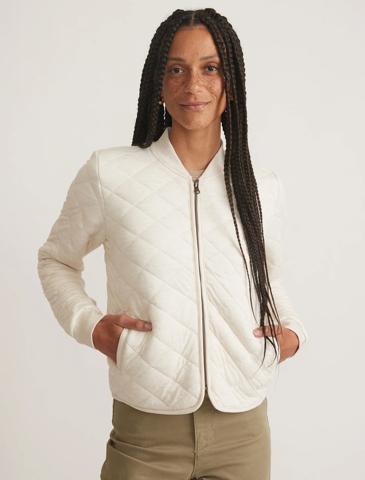 Model wearing Marine Layer's updated corbet quilted bomber in antique white.