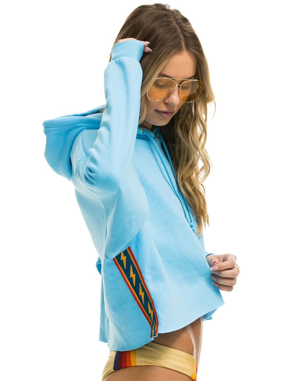 Model wearing Aviator Nation's bolt stripe relaxed cropped pullover hoodie in sky.