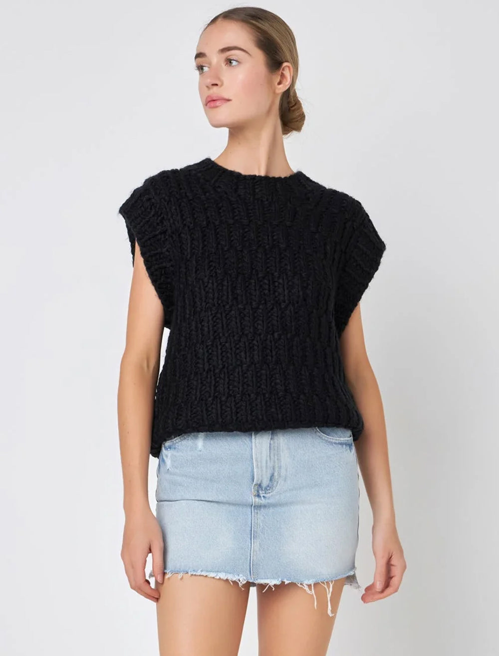 Model wearing English Factory's chunky knit sweater vest in black.