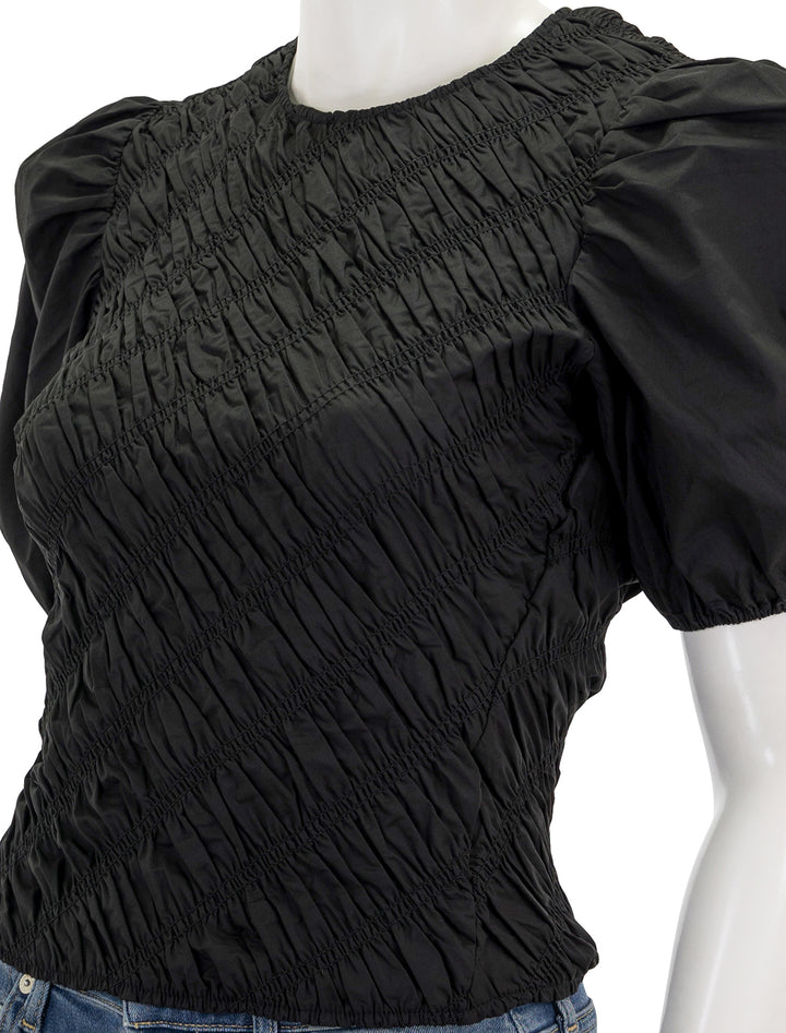 Close-up view of English Factory's asymmetrical smocked top in black.