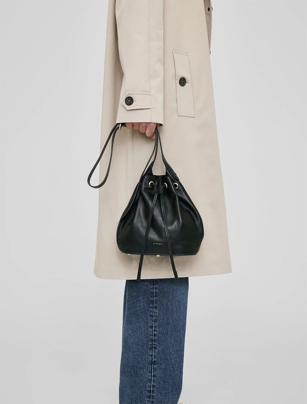 Model carrying Anine Bing's alana mini bucket bag in black.