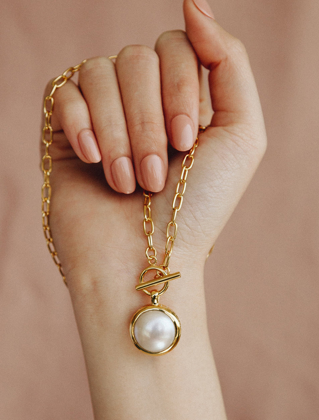 model holding coin pearl toggle chain necklace in gold