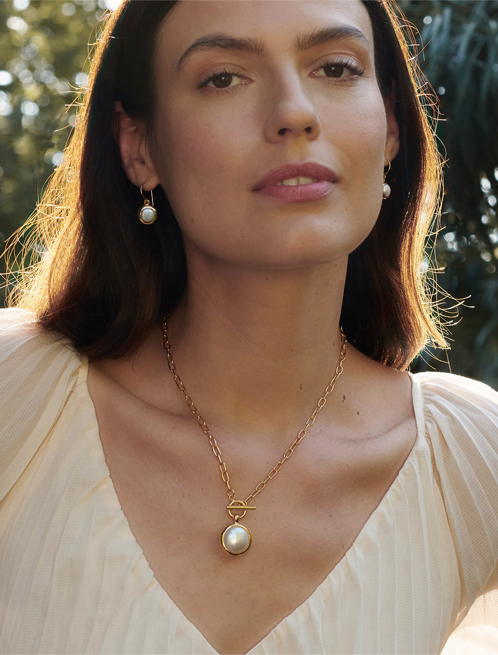 model wearing pearl drop earrings in gold