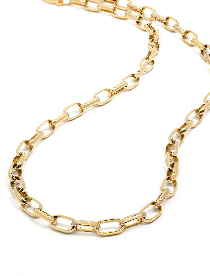 Stylized laydown of AV Max's small paperclip chain necklace in gold.