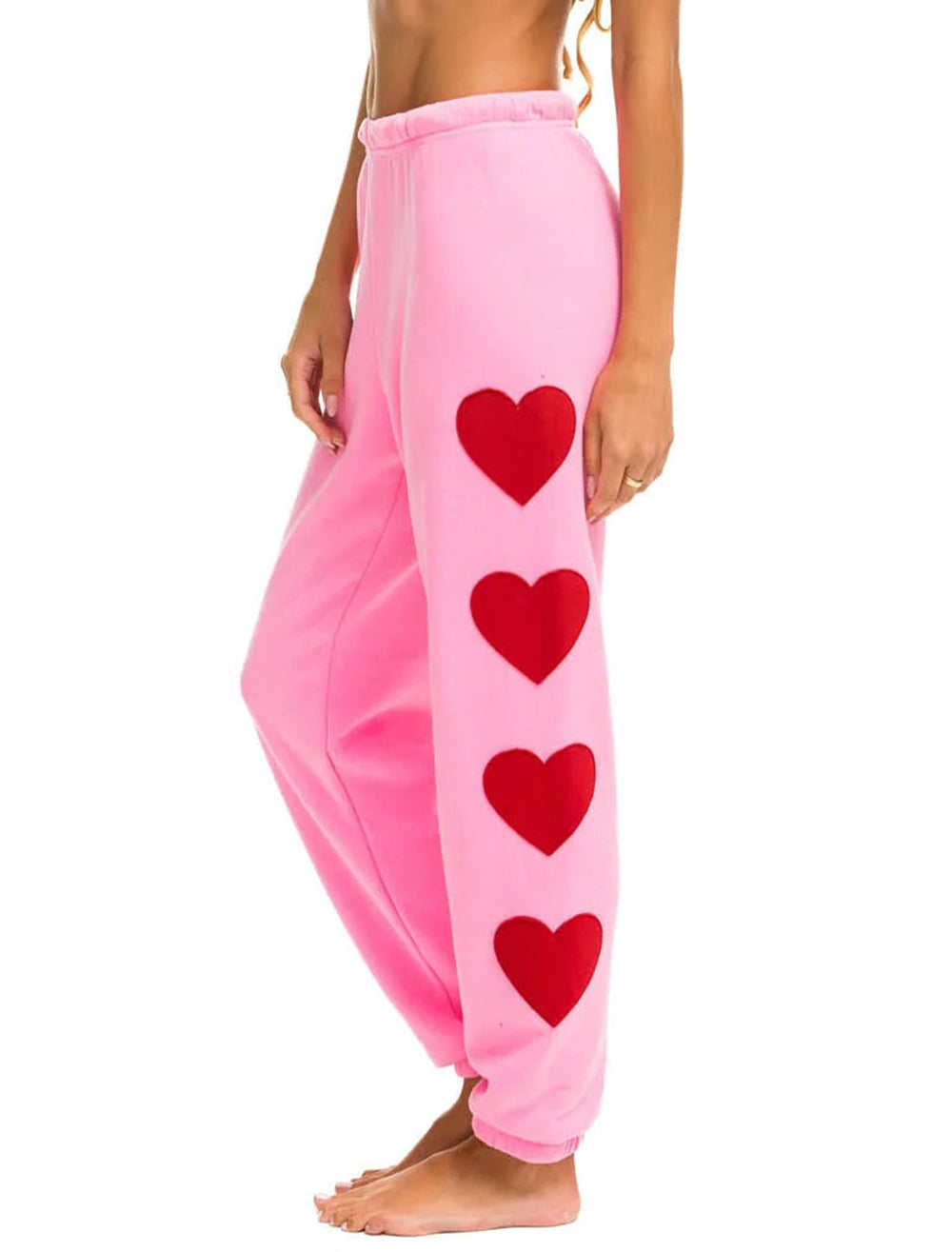 Model wearing Aviator Nation's heart stitch four sweatpants in pink.