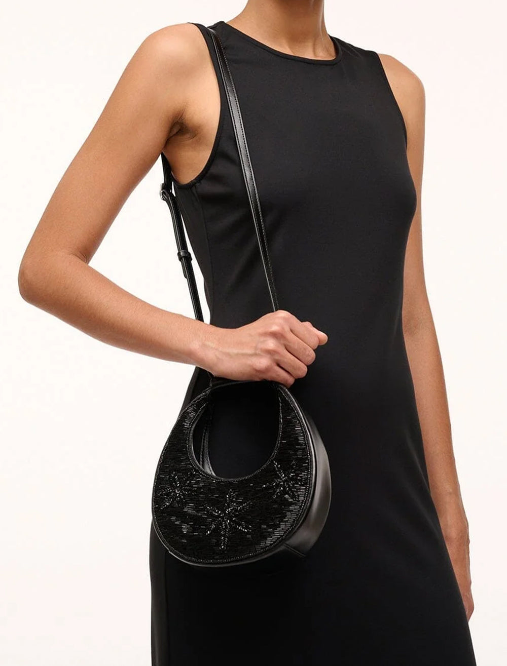 Model wearing STAUD's good night moon bag in black starfish on her shoulder.