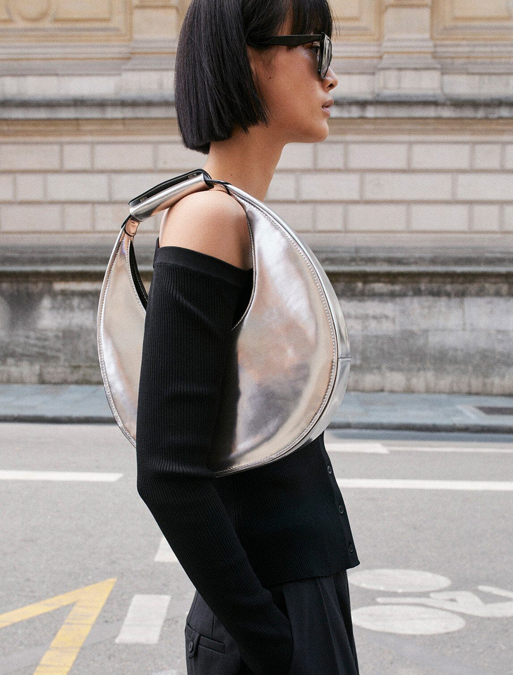 Model wearing STAUD's moon tote bag in chrome on her shoulder.