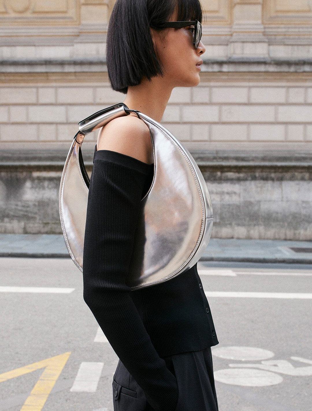 Model wearing STAUD's moon tote bag in chrome on her shoulder.